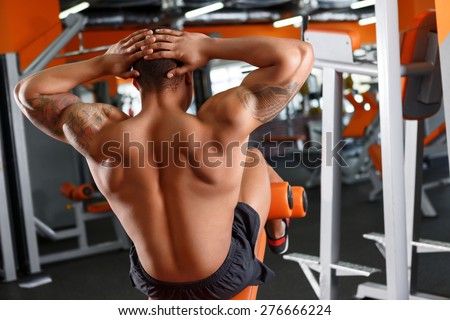 Strong back. Back view of man doing abdominal crunches in sport gym.