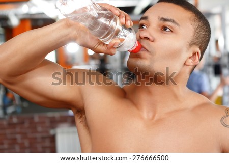 Water is life. Handsome young  man drinking water in sport gym after training.