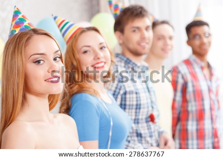 Happy friendship. Company of best friend wearing cone caps standing smiling in a row at the birthday party selected focus