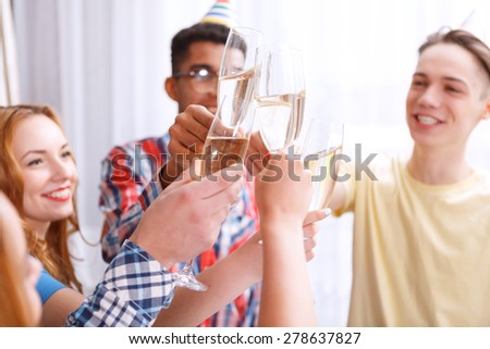 Celebration. Young people clinking glasses of champagne celebrating birthday of their friend selective focus