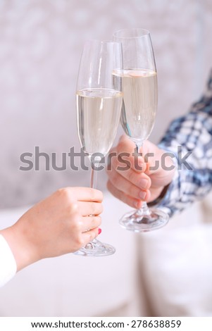 Party. Man and woman clinking glasses of champagne in the light room celebrating a birthday