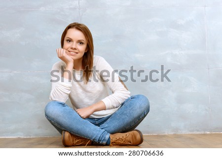 Thinking about you. Pleasant smiling young lady sitting cross-legged and leaning on her head on isolated background.