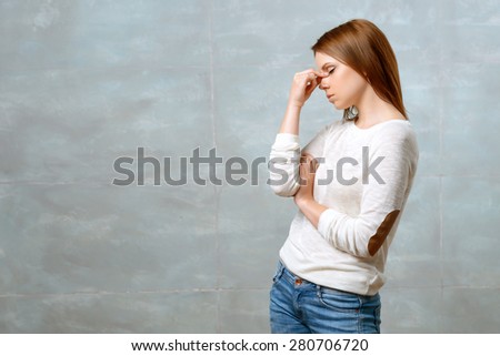 Feeling headache. Beautiful young woman standing and touching bridge of her nose with her fingers on isolated background.