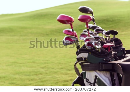 Fully equipped. Close up of bag full of different golf clubs on background of green course.