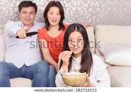 Dazzling view. Family of three people watching emotional film on TV