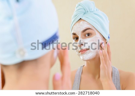 So beautiful.  Close-up of girl with beauty mask on her face looking in mirror.