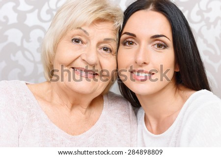 Closely together. Young and old smiling women sitting close to each other