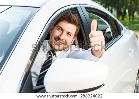 Thumbs up. Handsome smiling sitting in brand new car and man thumbing up .