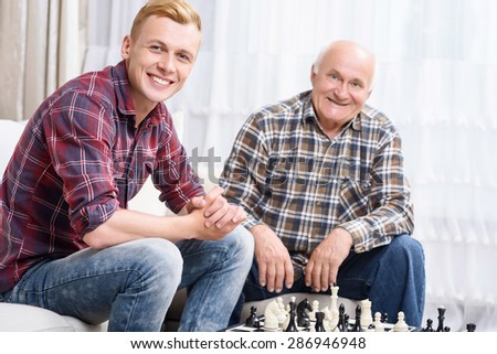 Happy players. Happy grandfather and grandson sitting on couch together  and playing chess.