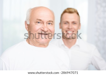 Two ages. Old man standing on background of his grandson