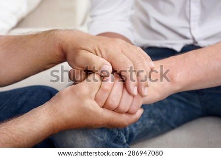 Opposite sides. Portrait of young and old man hands lying on each other.