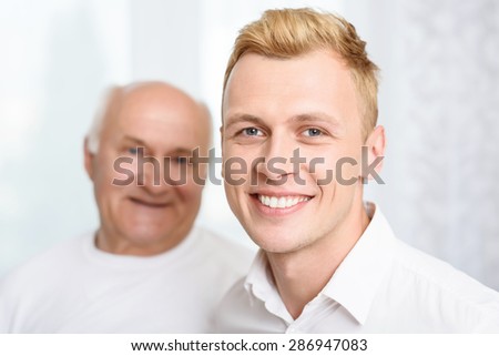 Different generations. Smiling grandson standing on background of his grandpa.