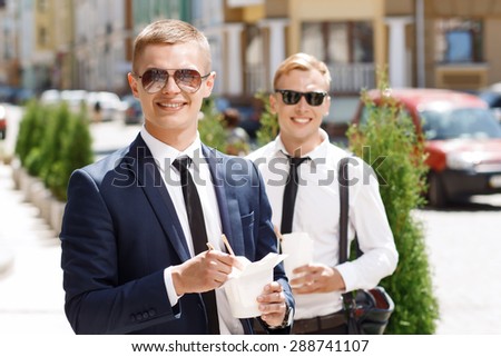 Happy pair. Portrait of young handsome men standing on street with Chinese fast food.