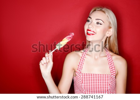 Sweet time. Cute young blond-haired woman holding candy on isolated red background