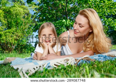 Lovely couple. Youthful beautiful mother and her little daughter lying on cover and having picnic in park