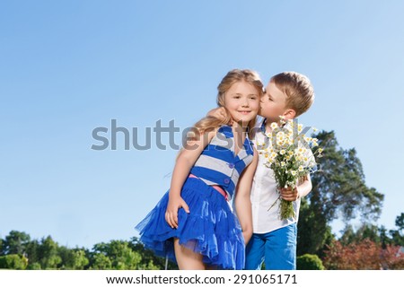 Forever together. Cute little boy holding the bunch of flowers and kissing his love heart while bonding to her.