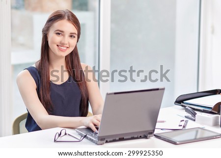 Good job. Cheerful diligent young business woman working with laptop and sitting at the table while reveling in positivity.