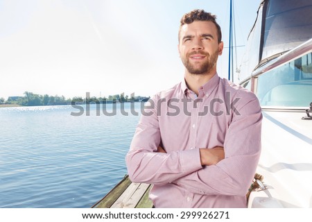 Want to relax after hard day. Pleasant handsome man bending his hands while going to sail on the deck of yacht.