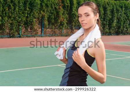 Find inspiration in sport. Good looking nice young woman holding towel with both hands on the neck before her tennis training.