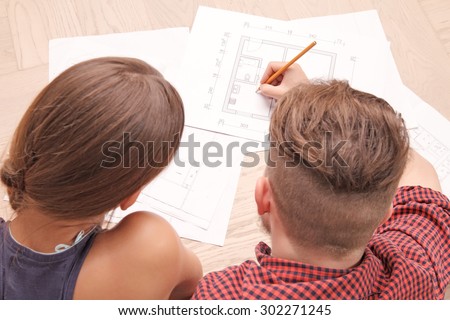 Happiness  in simple things. Top view of pleasant beautiful young couple lying on the floor and making plan of their new house together.