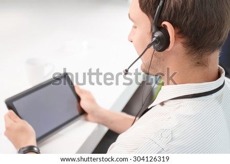 True professional. Top view of busy handsome call center operator holding laptop and doing his job while sitting at the table