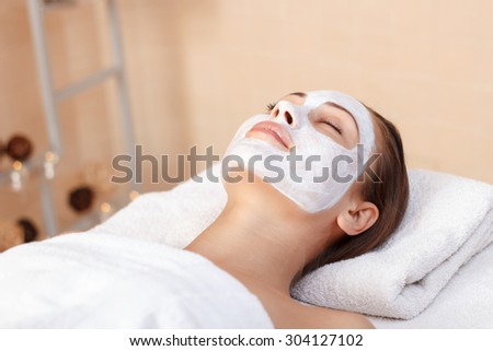 Relaxed and delighted. Pretty charming lady lying on the couch while reveling in spa procedure.