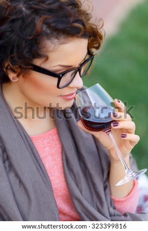 Like it so much. Pleasant delighted young appealing girl holding glass and reveling in drinking wine while expressing pleasure.