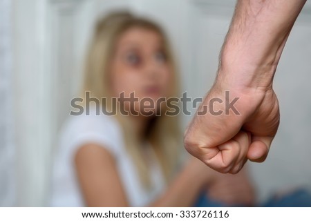 Cruel behavior. Close up of fist of a man going to chastise the girl sitting on the floor in the corner