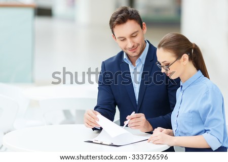 Paperwork routine. Two smiling employees are busy with form-filling maintenance