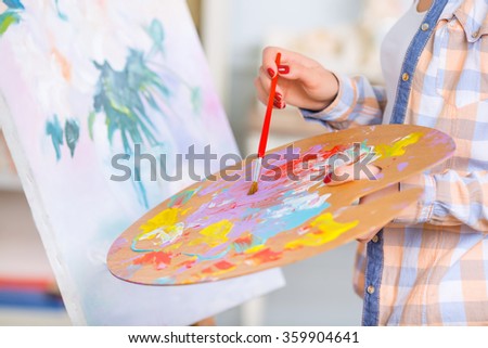 Young girl is busy oil-painting.