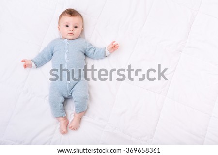 Curious little boy lying in bed.