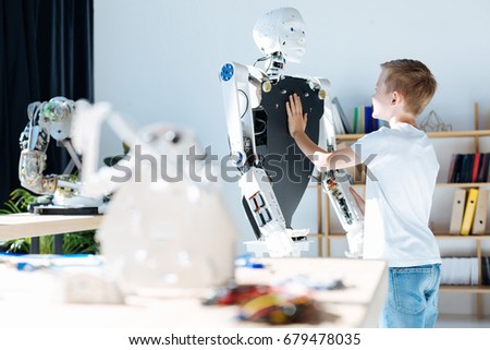 Fair-haired boy touching chest of a human robot