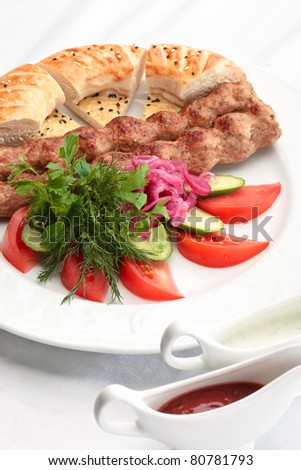 Chicken kebab with a side salad and bread decorated on a white background