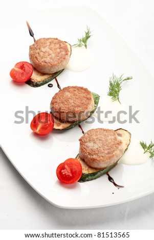 Russian chicken cutlets decorated with tomatoes and squash on a white background