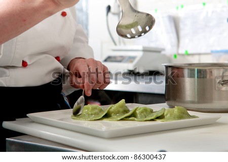 A chief cook masterly preparing delicious green ravioli with pesto sauce at the kitchen