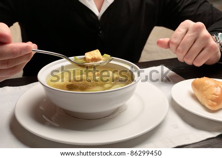 A young man eating fish soup, sitting at a table elegantly served in a restaurant, close up