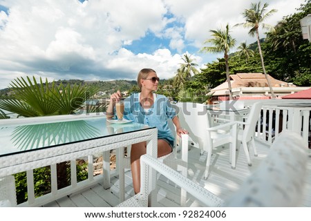 A young and attractive woman having a coffee break alone in an modern outdoor ocean view restaurant