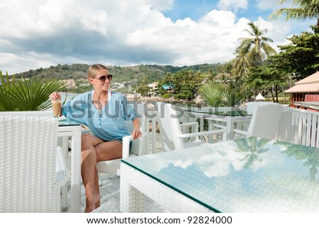 A young and attractive woman having a coffee break alone in an modern outdoor ocean view restaurant
