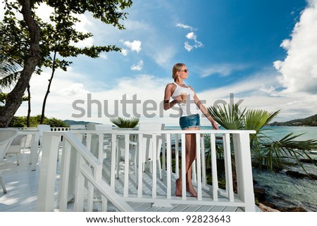 A young and attractive woman having a coffee break in an modern outdoor ocean view restaurant