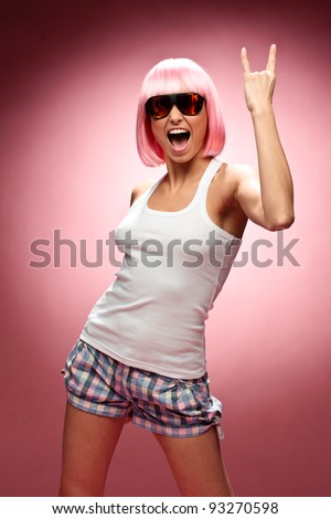 stock photo Funny young girl in pink wig and glasses dancing for camera