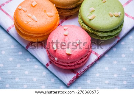 Macaroons put close together on blue table and white cloth with colorful and backlight.