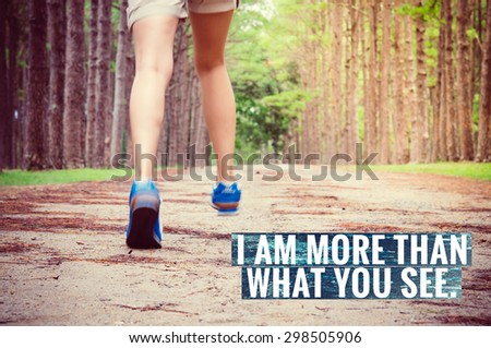 Inspirational quote on legs running through pine tree forest trail with blue running shoes.