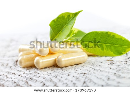 Capsules on white wooden background.
