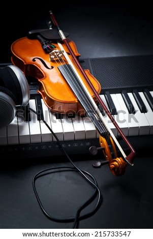 Violin, piano keys and headphones on black