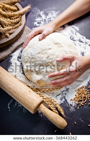 Professional female baker cooking dough. Baking background with dough, flour and rolling pin.