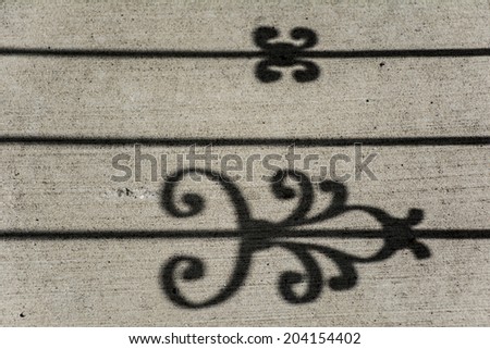 Art/design/pattern created by shadow of a metal gate falling on the concrete ground