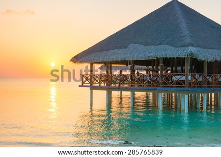 Sunset and silhouette of an over-water restaurant of an island resort
