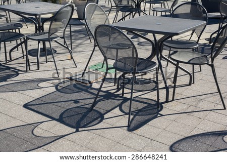 Tables and chairs with strong shadows under harsh sunlight in late afternoon