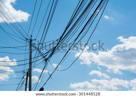 Telephone towers with connecting cables / lines against blue sky background. Communication technology