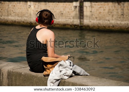 woman listening music with red Headphone in border Seine river in Paris